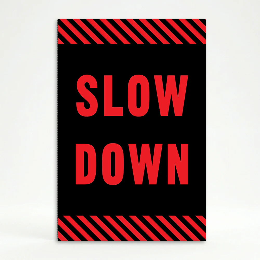 Slow Down sign with red text on black background and diagonal red and black hazard stripes