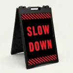 Slow Down sign with red text on black background and diagonal red and black hazard stripes