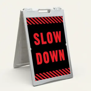 Slow Down sign with red text on black background and diagonal red and black hazard stripes