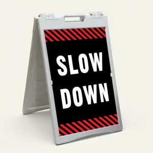 Slow Down sign with white text on black background and diagonal red and black hazard stripes