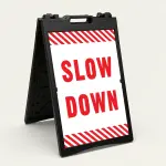 Slow Down sign with red text on white background and diagonal red and white hazard stripes