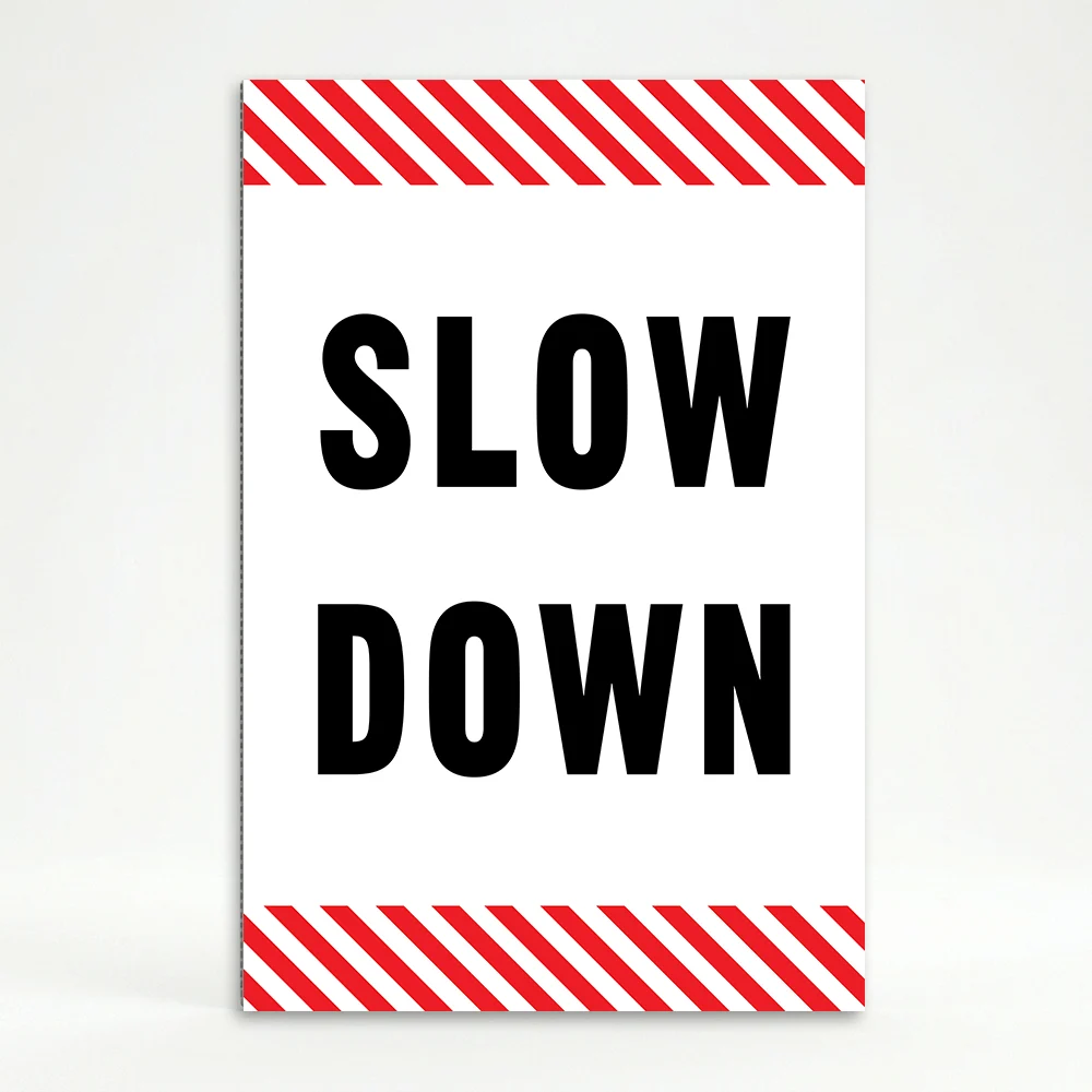 Slow Down sign with black text on white background and diagonal red and white hazard stripes