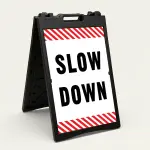 Slow Down sign with black text on white background and diagonal red and white hazard stripes