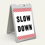 Slow Down sign with black text on white background and diagonal red and white hazard stripes
