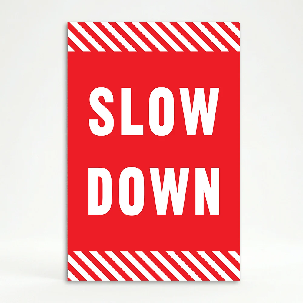 Slow Down sign with white text on red background and diagonal red and white hazard stripes