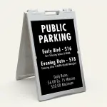 Custom multi-rate parking schedule A-frame sign with white text on black panel showing early bird rate, evening rate, and daily interval rate for Los Angeles parking lot