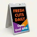 Custom black purple and orange geometric A-frame sign with bold orange message text on black panel and white additional text and phone number on colorful geometric lower section for Los Angeles creative business salon or cafe
