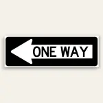 Black and white landscape One Way sign with full-size left-pointing arrow on the left and bold ONE WAY text on the right, rounded black border.