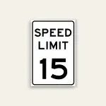 White portrait speed limit sign with rounded black border and black text reading SPEED LIMIT above a large numeral 15.