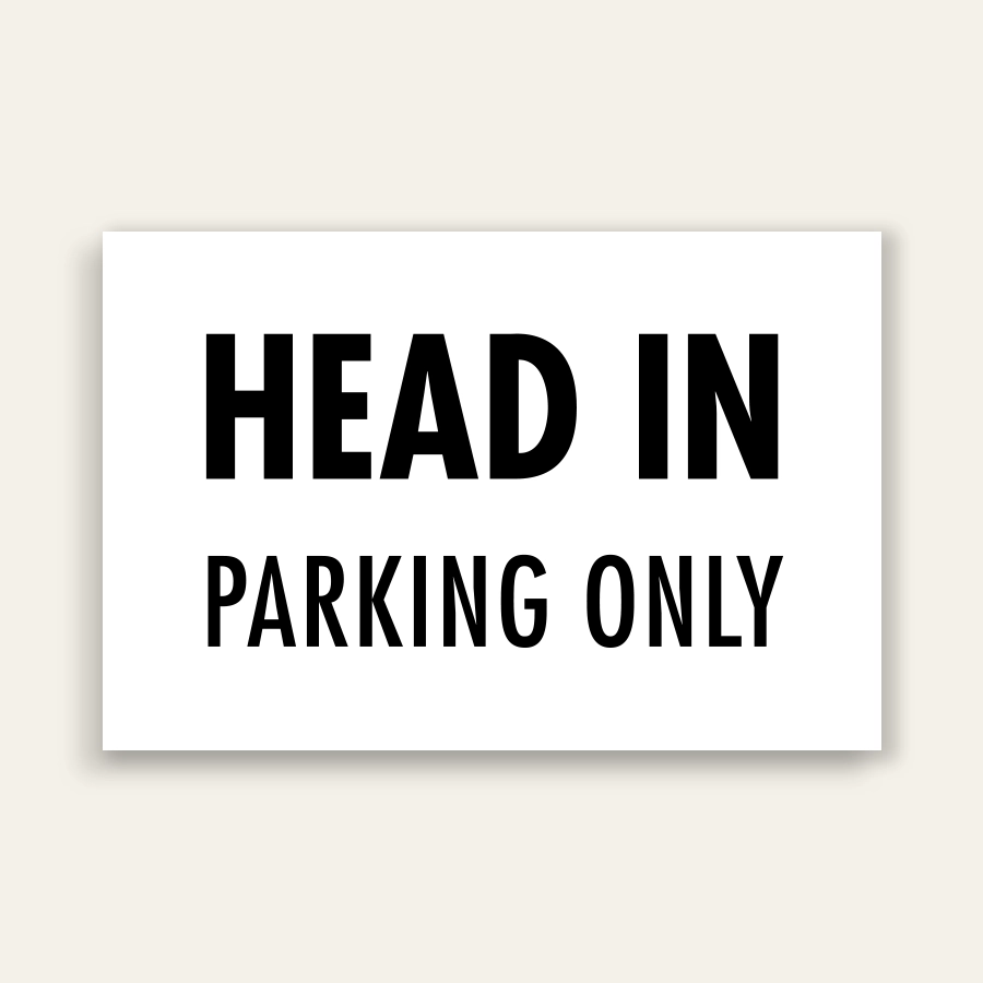 White landscape sign with bold black text reading HEAD IN above smaller PARKING ONLY text, no border.