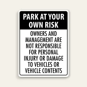 Black and white portrait sign with black header reading PARK AT YOUR OWN RISK above black text stating owners and management are not responsible for personal injury or damage to vehicles or vehicle contents.