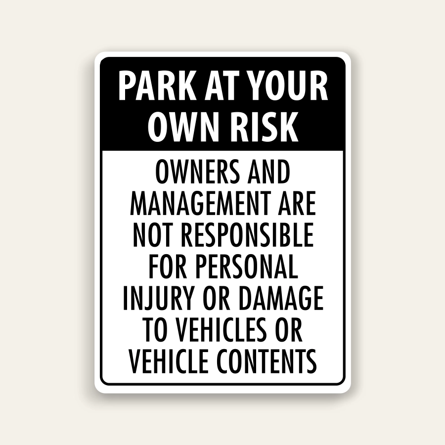 Black and white portrait sign with black header reading PARK AT YOUR OWN RISK above black text stating owners and management are not responsible for personal injury or damage to vehicles or vehicle contents.